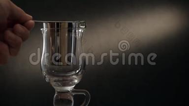 用金属过滤器在玻璃杯中冲泡茶。 一个男人的特写`手把茶倒进茶过滤器。